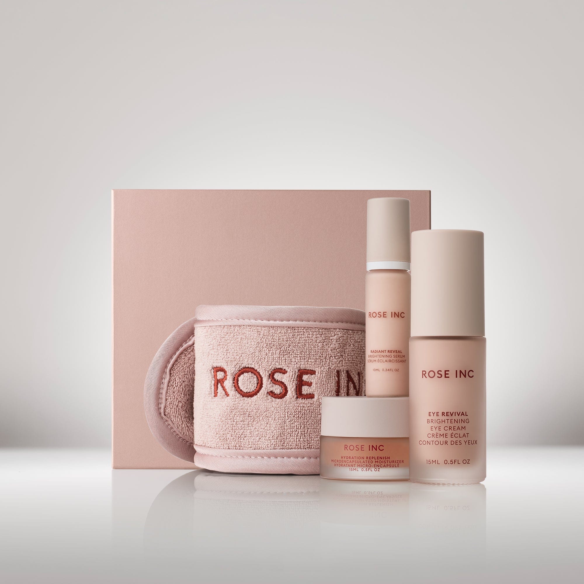Image of the Brightening Essentials Set which includes the Eye Revival Brightening Eye Cream, Travel Size Radiant Reveal Brightening Serum, Travel Size Hydration Replenish Moisturizer and Rose Inc. Spa Headband.
